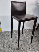 Full view of barstool showing leather seat, back, legs, chrome footrest
