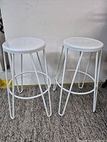 Both white metal bar stools side by side showing full structure