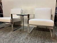 Pair of white leatherette accent chairs beside small table