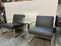 Pair of gray faux leather chairs beside small table