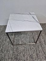 Full view of square marble top table on chrome frame
