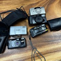Front view of four compact film cameras with two cases