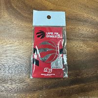 Front view of sealed Toronto Raptors lapel pin packaging