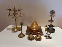 Full lot showing all brass candle holders, conical brass decor on wood base, and electric candle wick holder