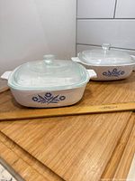 Both CorningWare dishes with lids on wooden board