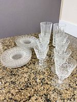 Plates stacked beside lineup of assorted crystal glasses