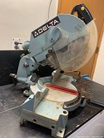 Full view of Delta miter saw showing body, base, handle, and blade guard