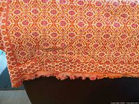 Full view of patterned silk bedspread draped over surface