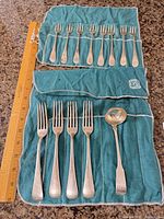 Top view of all 13 sterling flatware pieces in cloth rolls