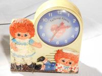 Front and slightly angled view of the retro alarm clock featuring Raggedy Ann and Andy 3D figures on a cream base, clock face shows heart with 'I Love You' and 'Talking Alarm' text.