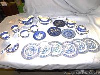 Full set of blue and white china dishes displayed on cloth background, visible various plates, cups, creamers, sugar bowl, and serving pieces.