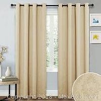 Example installation of beige grommet top drapes hanging on curtain rod in a window.