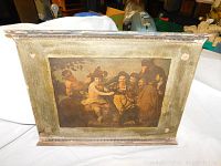 Front view of a wooden framed art piece showing a classic group painting with decorative molding and signs of wear.