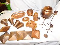 Full display of all copper items for lot, showing trays, vases, kettle, and candle holders.