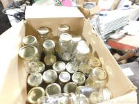 Box filled with assorted clear glass canning jars with metal lids in various sizes.