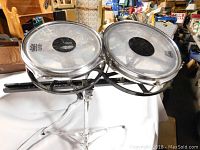 Front view of a pair of timbales drums with Remo drumheads mounted on a metal tripod stand.