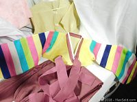 Shows bright jeogori with colorful stripes on sleeves laid out with a maroon skirt, highlighting the garment details and colors.