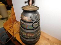 Close-up photo focusing on the painted floral and geometric patterns on the lamp's tiered metal base.
