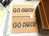 Two rectangular coir door mats with 'GO AWAY' printed in black text.