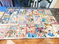 Full view of 22 vintage comic books laid out on a table including multiple issues of X-Men, Cloak & Dagger, Fantastic Four, and more.