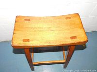 Top-down view showing the curved wooden seat and four small rectangular patches reinforcing the seat corners.