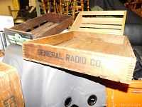 Photo showing three vintage wooden crates stacked on a table, including one branded "General Radio Co".