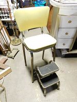 Full view of vintage stool with yellow vinyl seat and back. Fold-out two-step ladder is open beneath the seat.