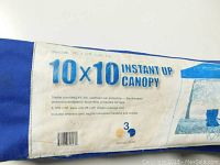 Photo of the blue carrying bag with label displaying '10x10 Instant Up Canopy' and product specifications such as UV protection and coverage area.