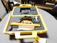 Photo showing yellow Berger Model 110 survey instrument and accessories inside fitted foam case compartments.