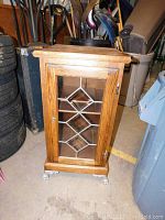 Front view of wooden cabinet with decorative glass front door and silver claw feet.