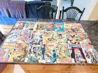Top-down view of 20 vintage comic books laid out on a table showing colorful superhero cover art, titles visible such as Transformers, G.I. Joe, Power Pack, and The Mutants.