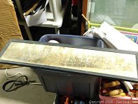 Full view of the framed panoramic photo placed on a plastic bin, showing the long rectangular frame and glass covering the photo.