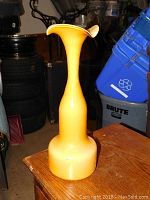 Side view of the tall yellow glass vase showing its flared top and wide base.