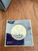 Coin in holder showing reverse with map and dates