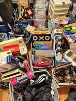 Overhead view of multiple bins showing wide variety of items including speakers, View-Master, cookware, helmet, goblets, organiser and games