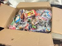 Open cardboard box filled with sealed Happy Meal toys