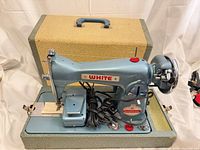 Full view of White teal sewing machine mounted in hard case with cords and pedal visible