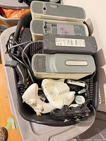 Basket containing three Xbox 360 consoles, power bricks, controllers