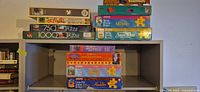 Two stacks of boxed puzzles on shelf showing all visible titles and brands