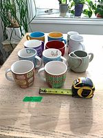 All eleven mugs arranged on table with measuring tape
