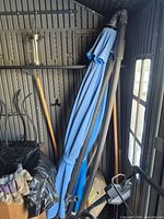 Folded blue patio umbrella standing in shed