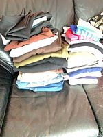 Stack of assorted folded women’s clothing on couch