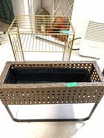 Planter on black stand in front, gold wire rack behind