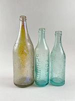 Front view of all three embossed Toronto soda bottles grouped by size
