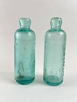 Front view of both aqua blob-top bottles standing