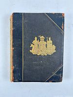 Front cover showing black leather/cloth boards with gilt crest, visible edge wear
