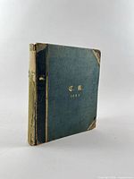 Closed album showing cover, gilt monogram and date 1883