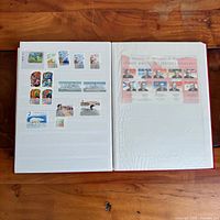 Album open showing assorted individual Canadian stamps on left page and pane of Canadian premiers on right