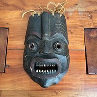front view of carved wooden mask with rope hair