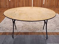 Full view of round plywood folding table on legs